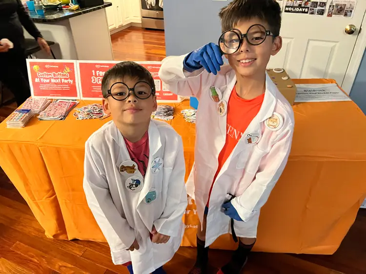 Two young buttonologists in lab coats beside their button table